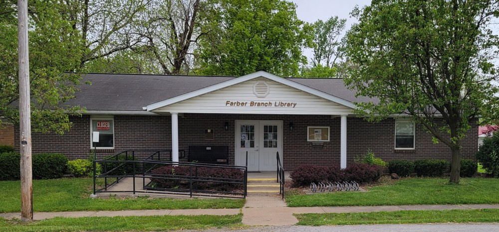 The Farber Library is a red brick, single level building with white double doors. 